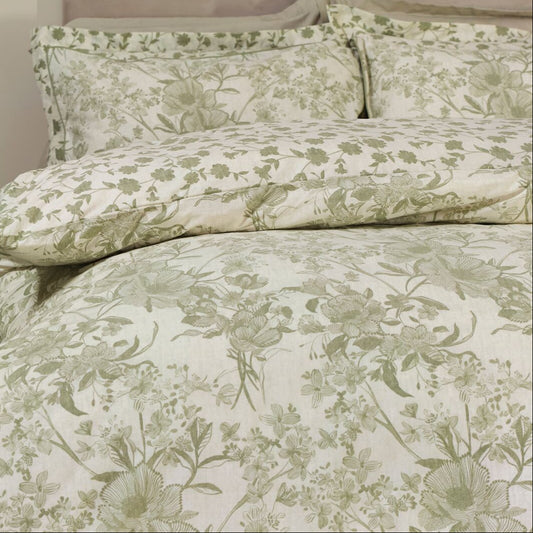 Floral patterned bedding set on a bed in a bedroom setting with a green chair and plant.
