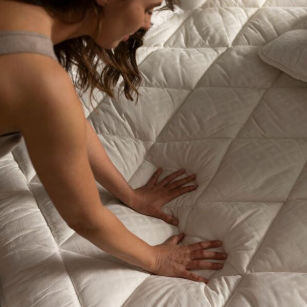 Person touching a mattress to check its comfort