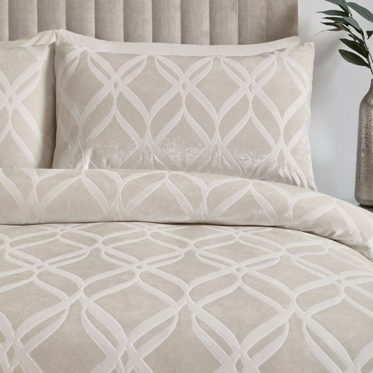 Beige and white geometric patterned bedding set on a bed with a neutral headboard.