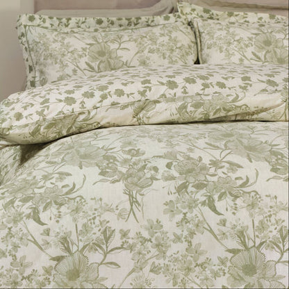 Floral patterned bedding set on a bed in a bedroom setting with a green chair and plant.