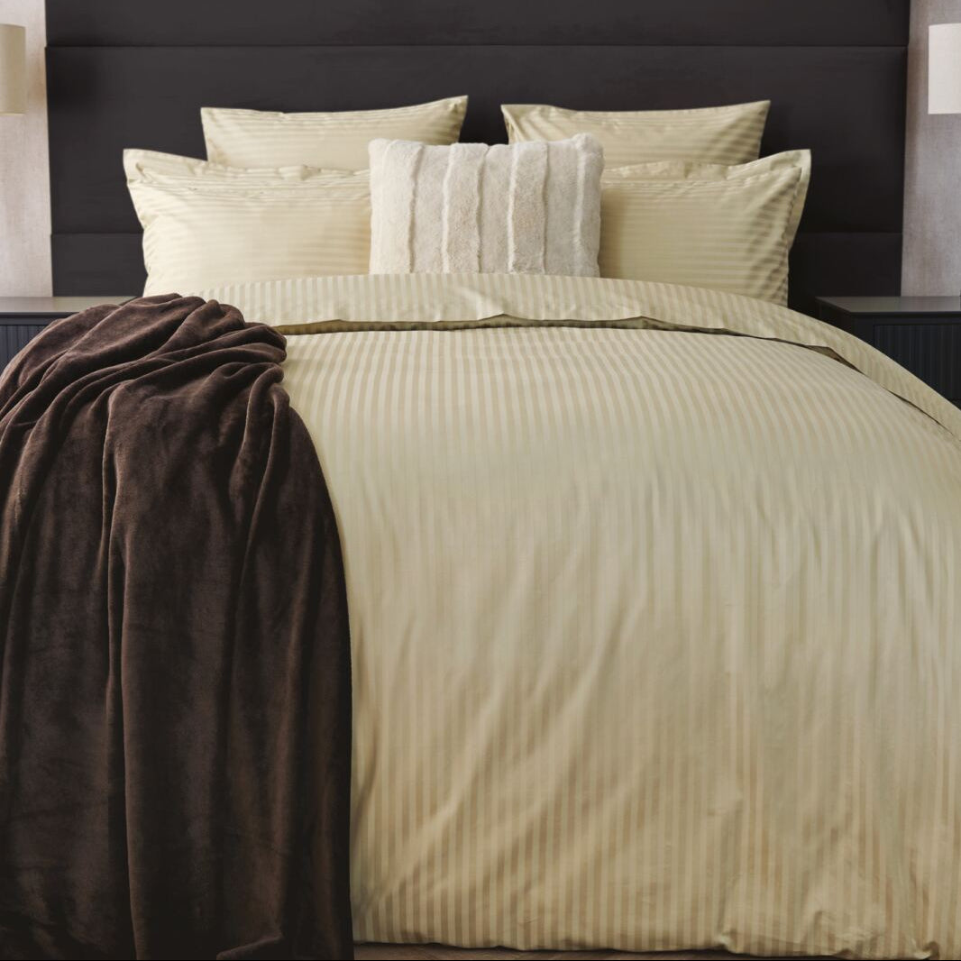 Neatly made bed with beige bedding and pillows in a bedroom setting.