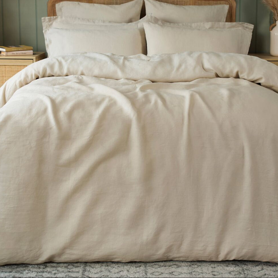 Neatly made bed with beige bedding in a bedroom setting.