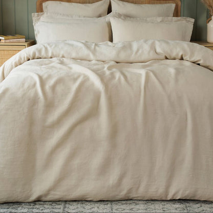 Neatly made bed with beige bedding in a bedroom setting.