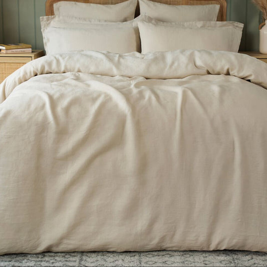 Neatly made bed with beige bedding in a bedroom setting.