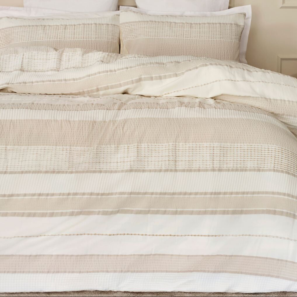 Neatly made bed with striped bedding in a bedroom setting.