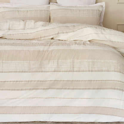 Neatly made bed with striped bedding in a bedroom setting.