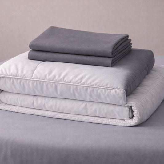 Folded gray and white blankets on a gray surface