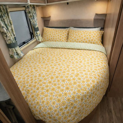 Compact bedroom setup inside a vehicle with yellow floral bedding.