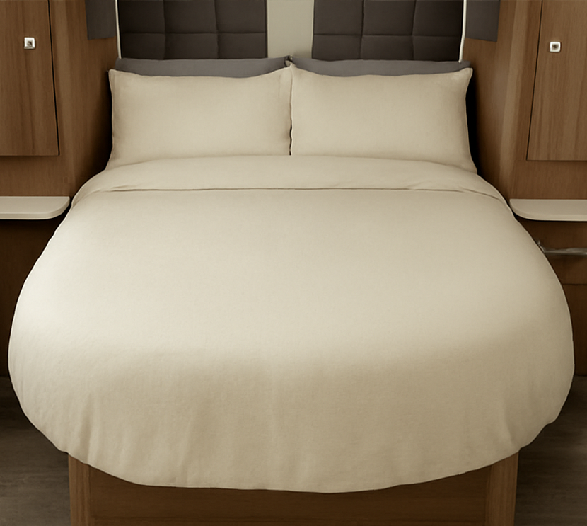 Beige bedspread on a bed with a brown headboard in a caravan setting