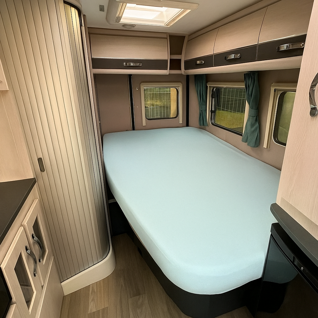 Compact bedroom interior of a vehicle with a bed, windows, and cabinets.