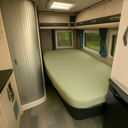 Compact bedroom setup inside a vehicle with a bed, window, and storage compartments.