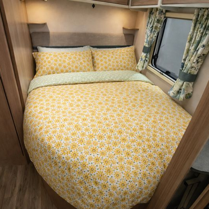 Bed with yellow floral bedding in a compact living space, possibly inside a vehicle or small home.