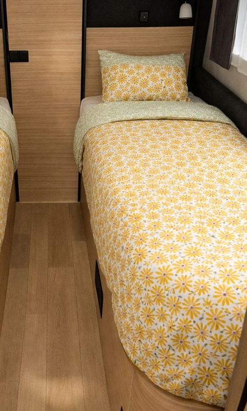 Bed with yellow floral bedding in a compact bedroom setting