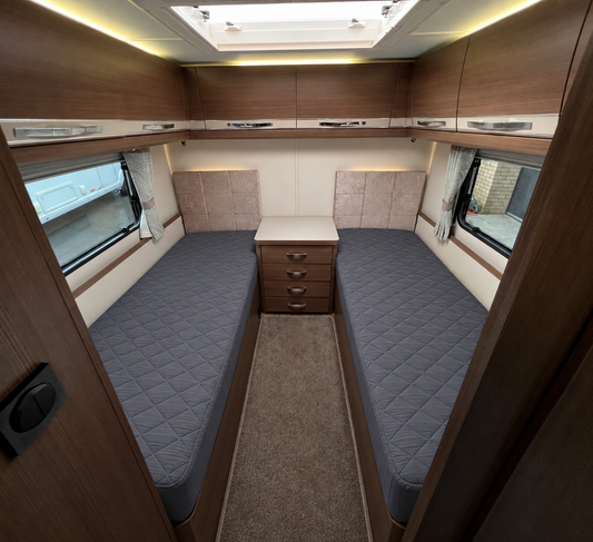 twin beds in a caravan with grey mattress protectors on